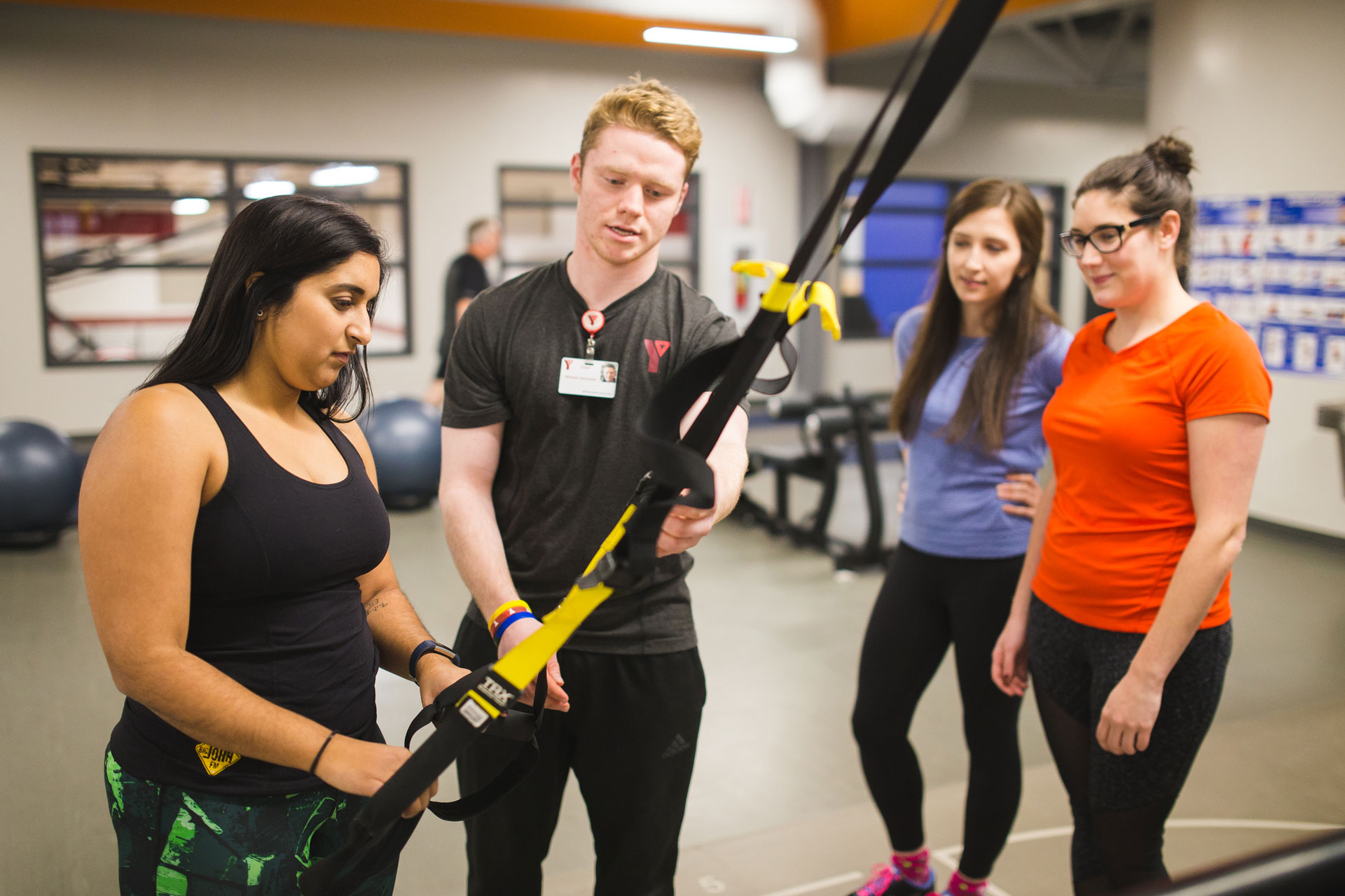 group coaching YMCA staff person showing members how to use TRX bands