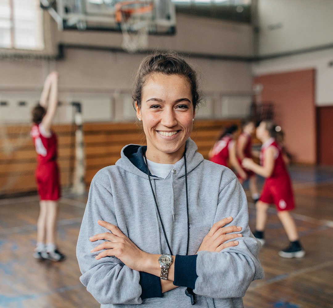 volunteer - mentor basketball coach in gymnasium with team playing behind
