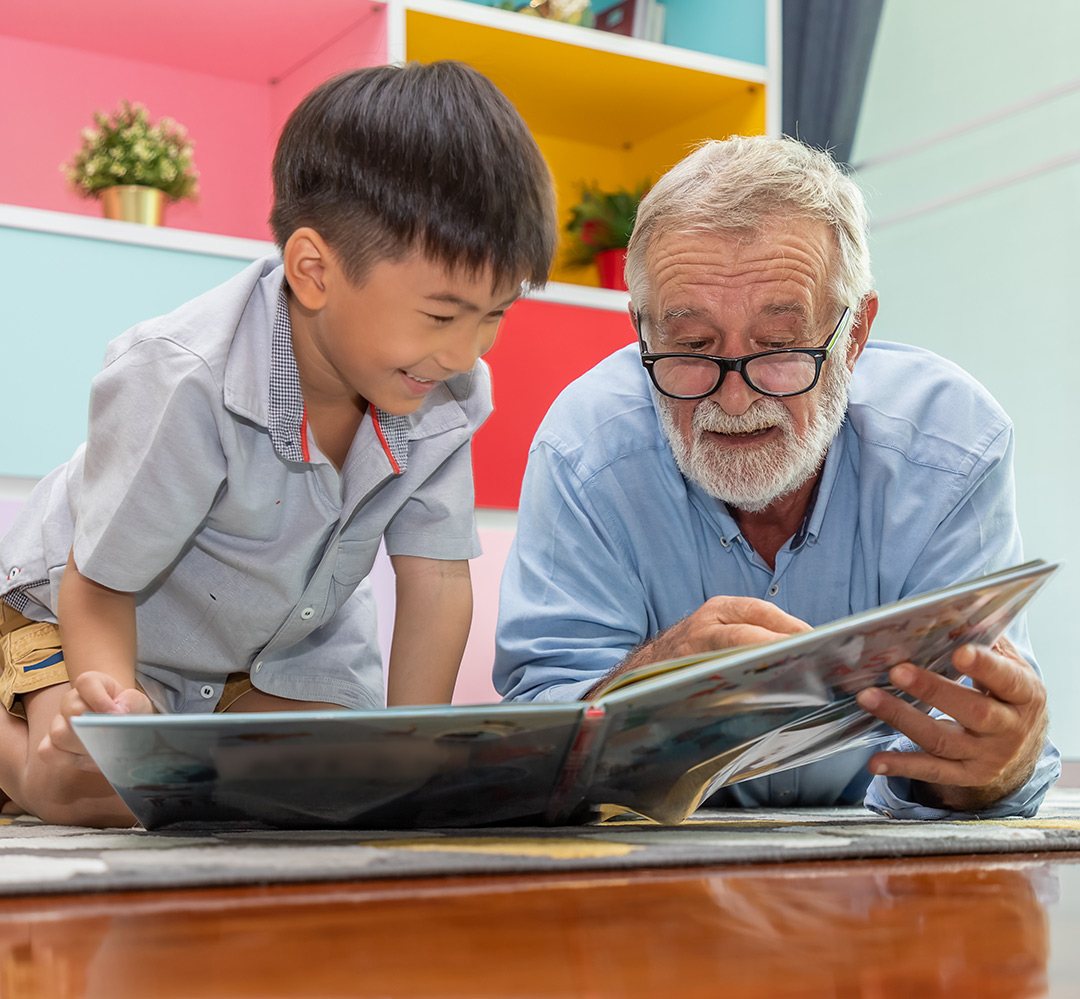 volunteer - kids are amazing man with white hair, beard and glasses reads book to young child