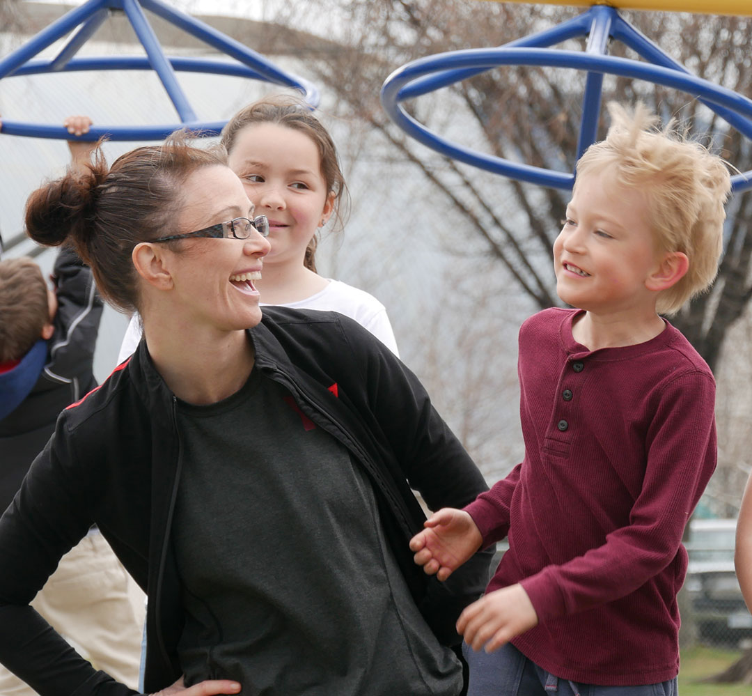 Queen's Park staff and kids (teaser) Staff and children laughing in playground at Queen's Park YMCA Child Care