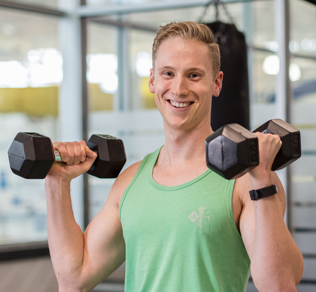 Student Membership (teaser) young man lifting dumbbells smiling at camera