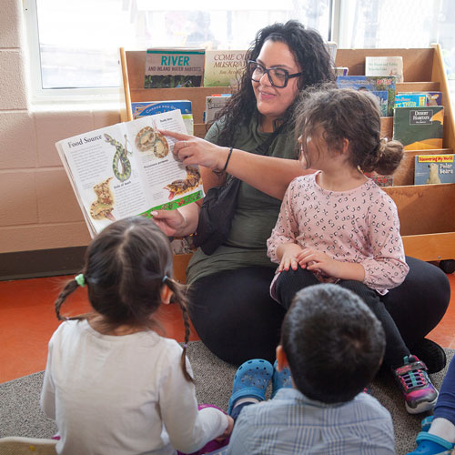 YMCA child care staff reading a book about snakes to children