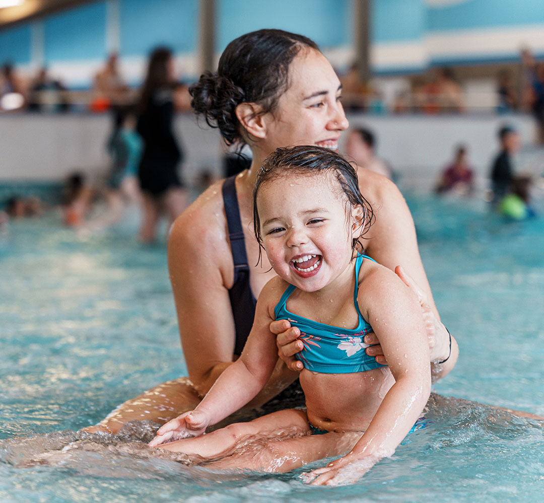 mother and young child having fun in a shallow pool area