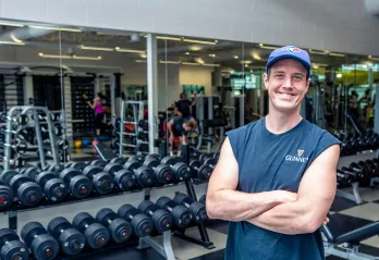 Austin smiling in front of the free weights