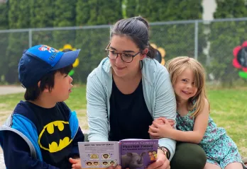 2 children and a woman reading a book