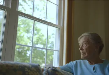 woamn in a white sweater looking out a window