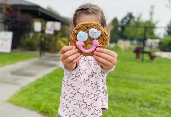 Kid holding up cookie on face