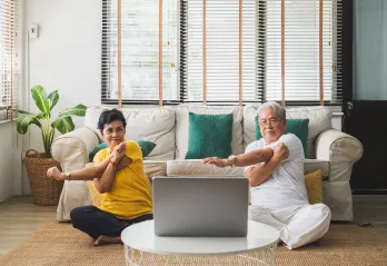 2 seniors stretching at home with a computer
