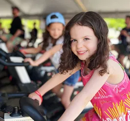 smiling girl riding stationary bike YMCA Cycle for Strong Kids