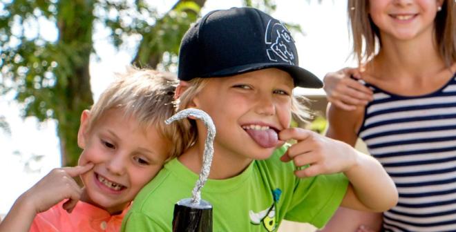 kids make silly face while holding pirate hook made of tin foil and cup