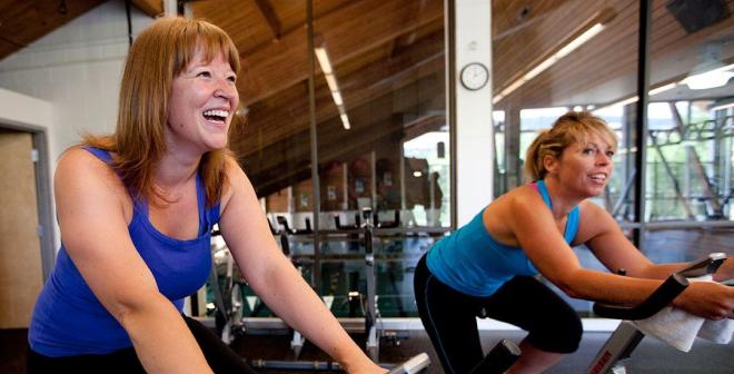 ladies smiling while exercising on stationary bicycles