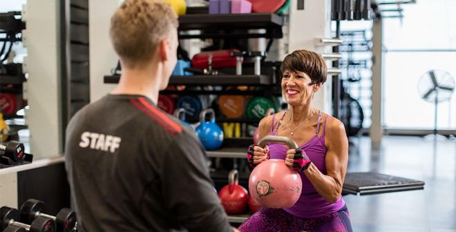 YMCA personal trainer instructs member on kettle bell squats