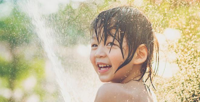 happy boy playing with water in sunshine