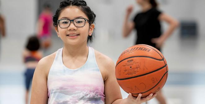 girl with glasses holding basketball