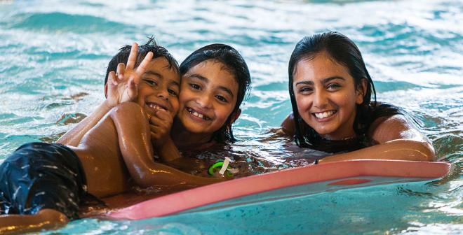 happy children floating on a mat in swimming pool