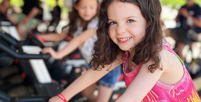 smiling girl riding stationary bike YMCA Cycle for Strong Kids
