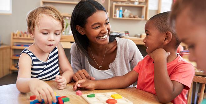 child care worker helping children with shape puzzle