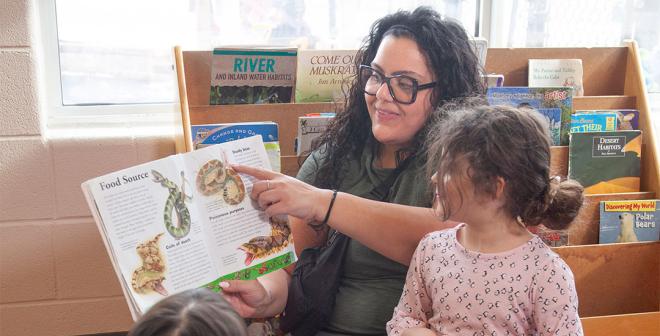 YMCA child care staff reading a book about snakes to children