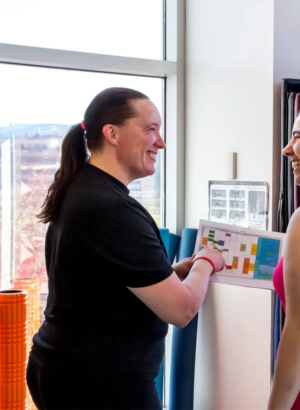 Two women consulting a printed schedule at H2O