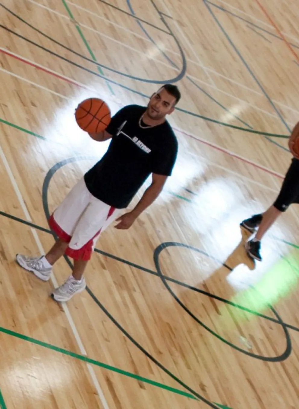 three young men playing basketball in the Kelowna Family Y gymnasium