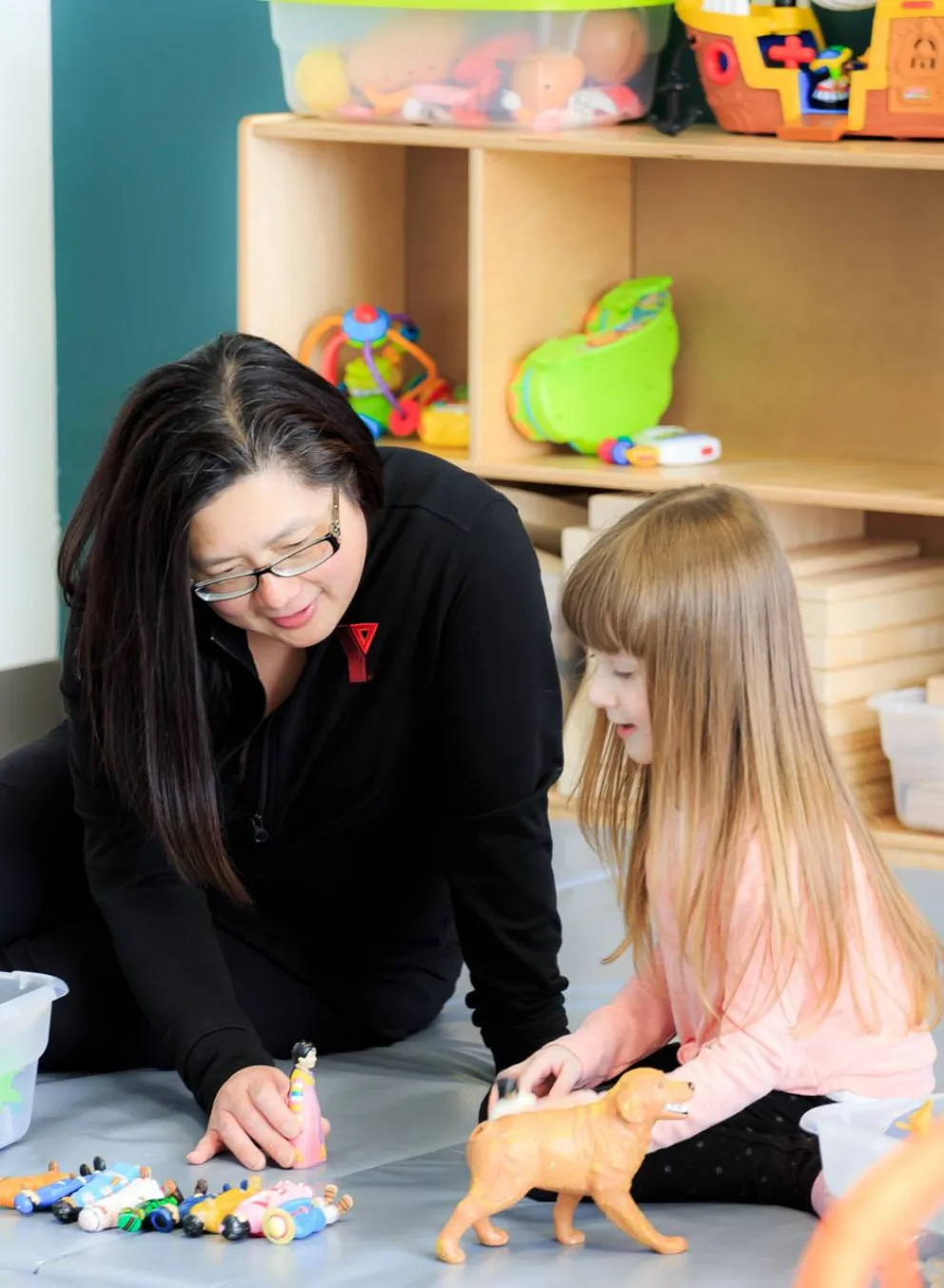 YMCA early childhood educator and child play imaginative game with toys