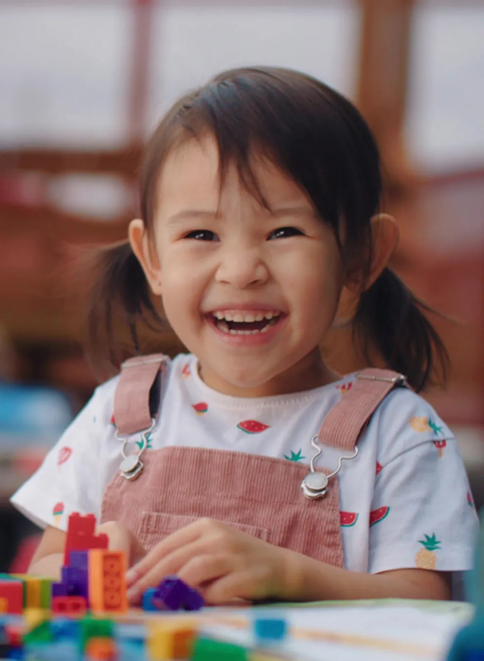 smiling child at table with LEGO blocks