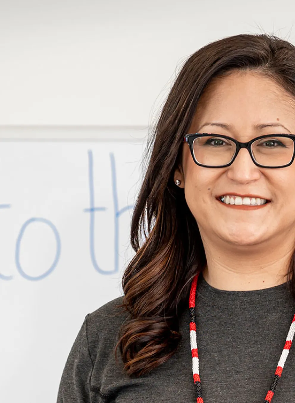 Smiling employee in front of whiteboard that says Welcome to the YMCA