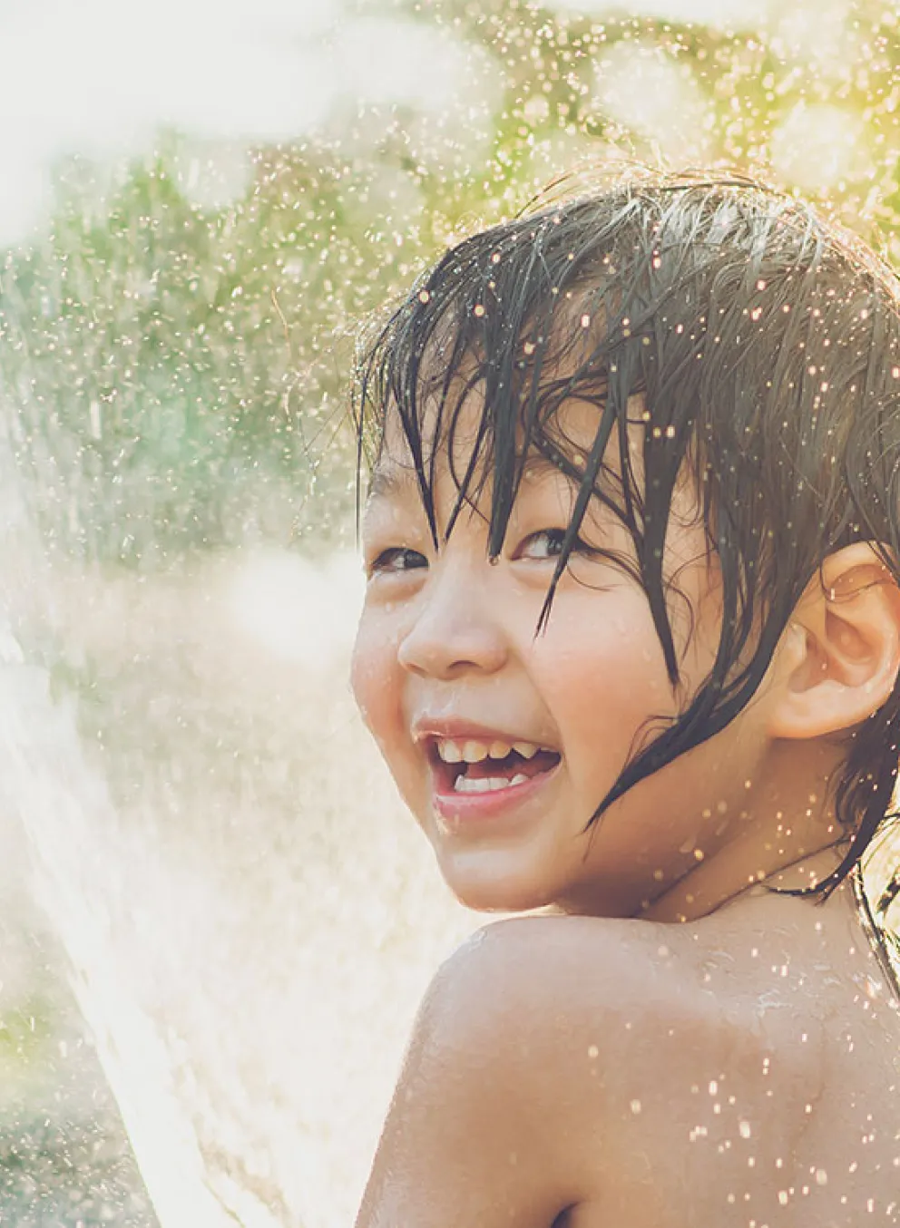 happy child playing with water in sunshine