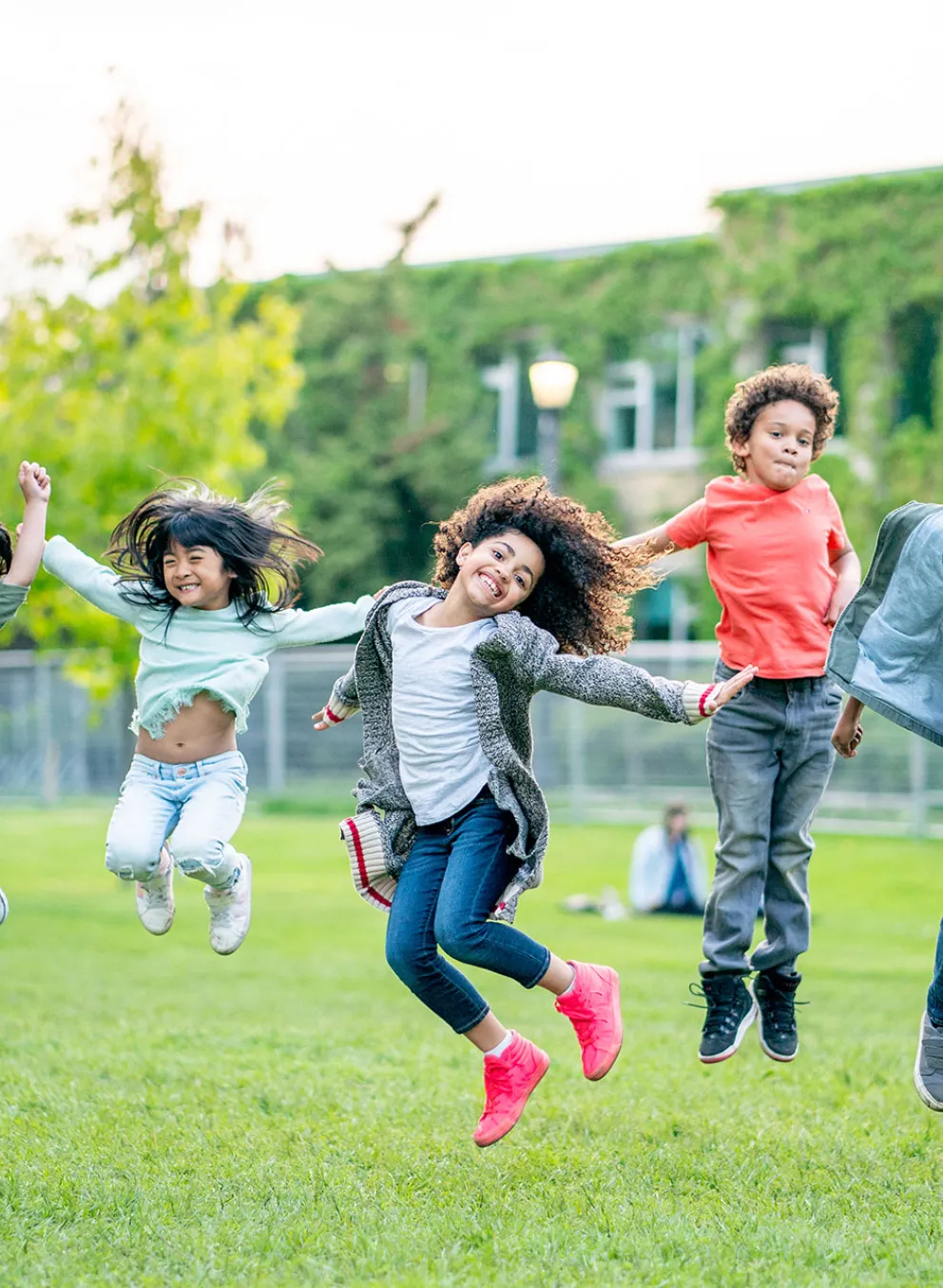group of children jumping in a grassy field