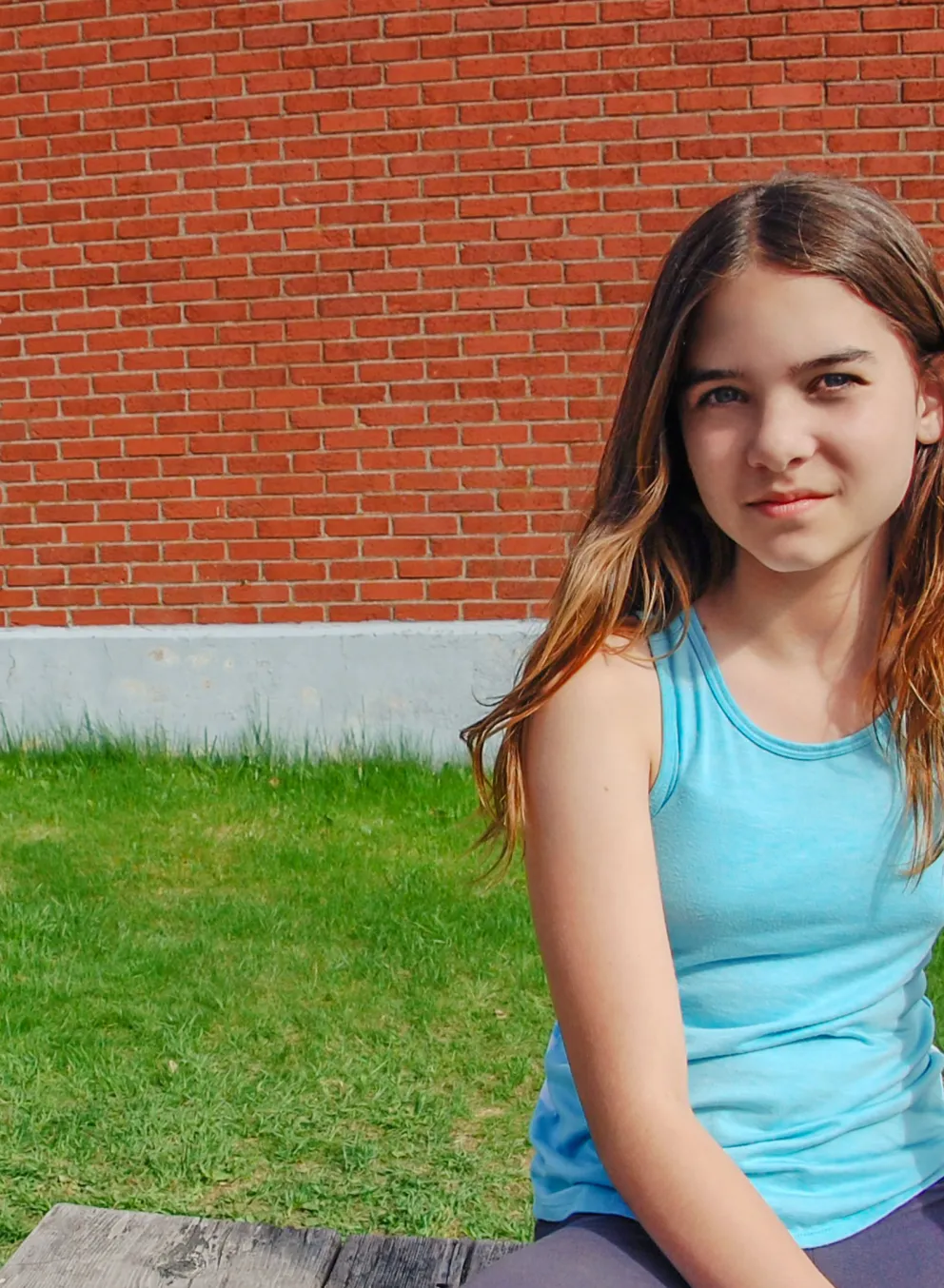 school-aged youth sitting in front of brick building