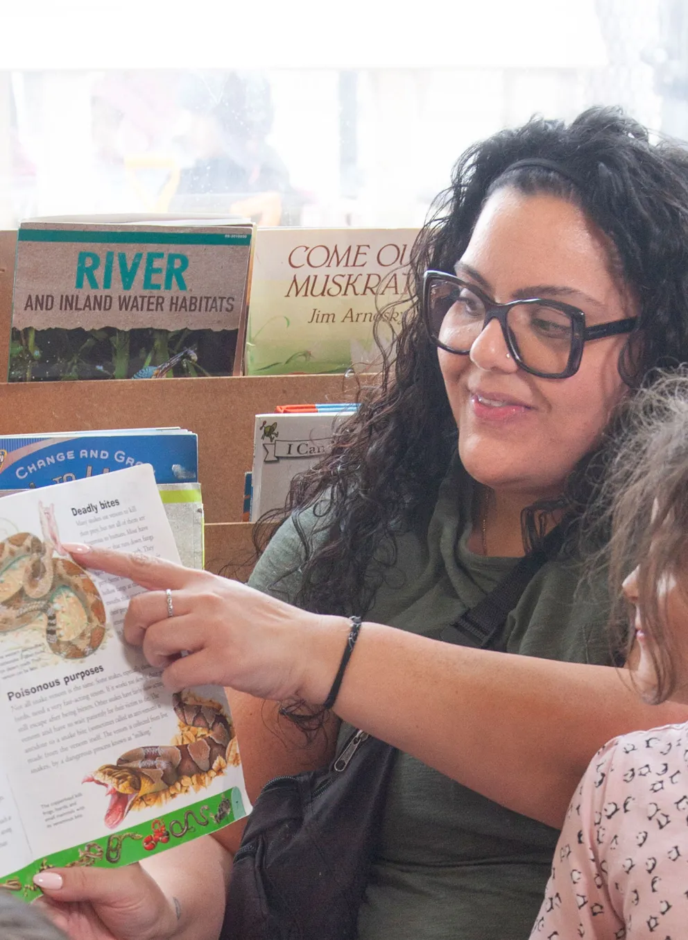 child care worker reading a book about snakes to children