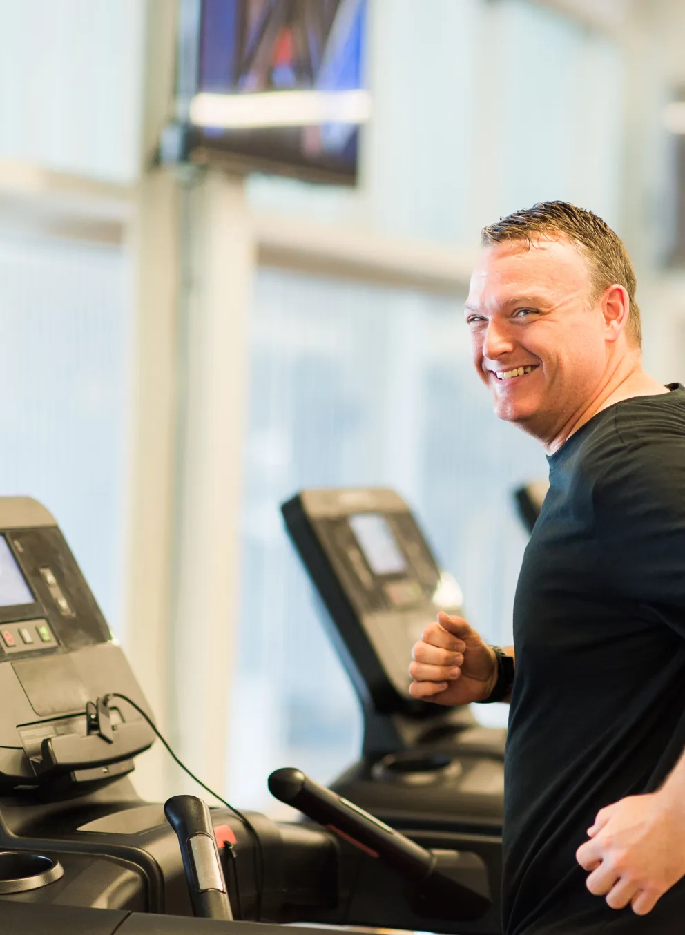 happy middle-aged man jogging on treadmill