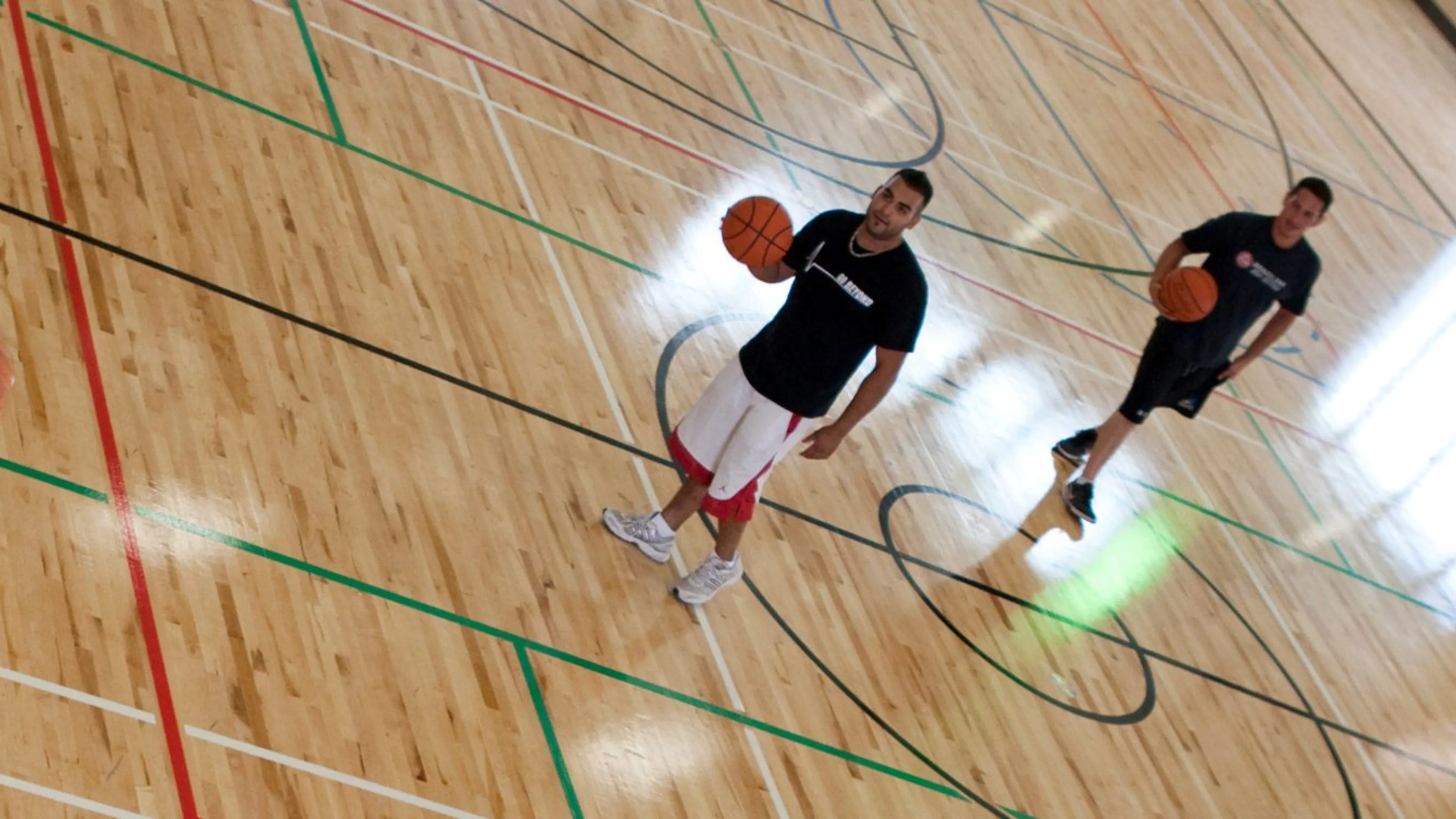 three young men playing basketball in the Kelowna Family Y gymnasium