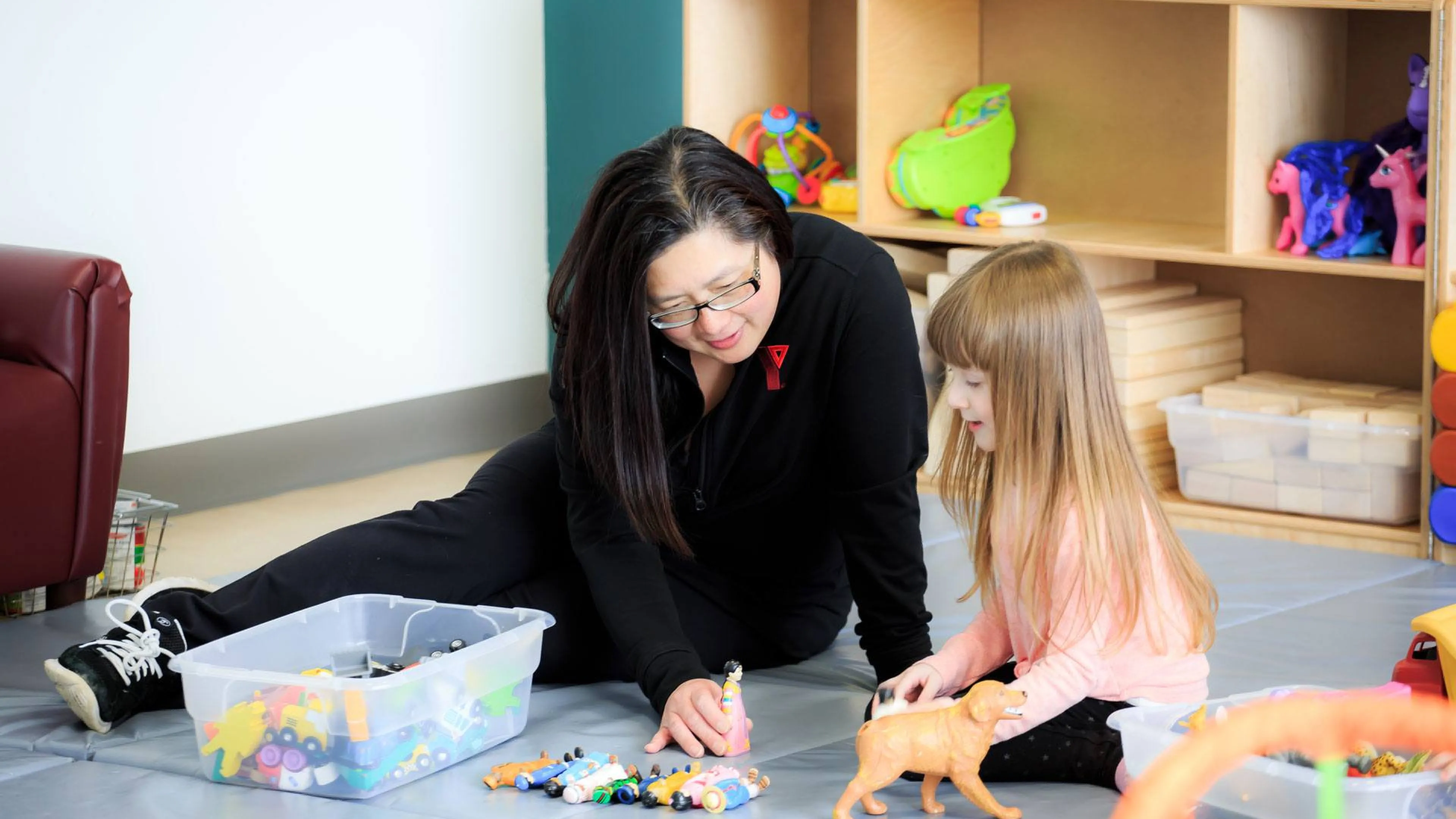 YMCA early childhood educator and child play imaginative game with toys
