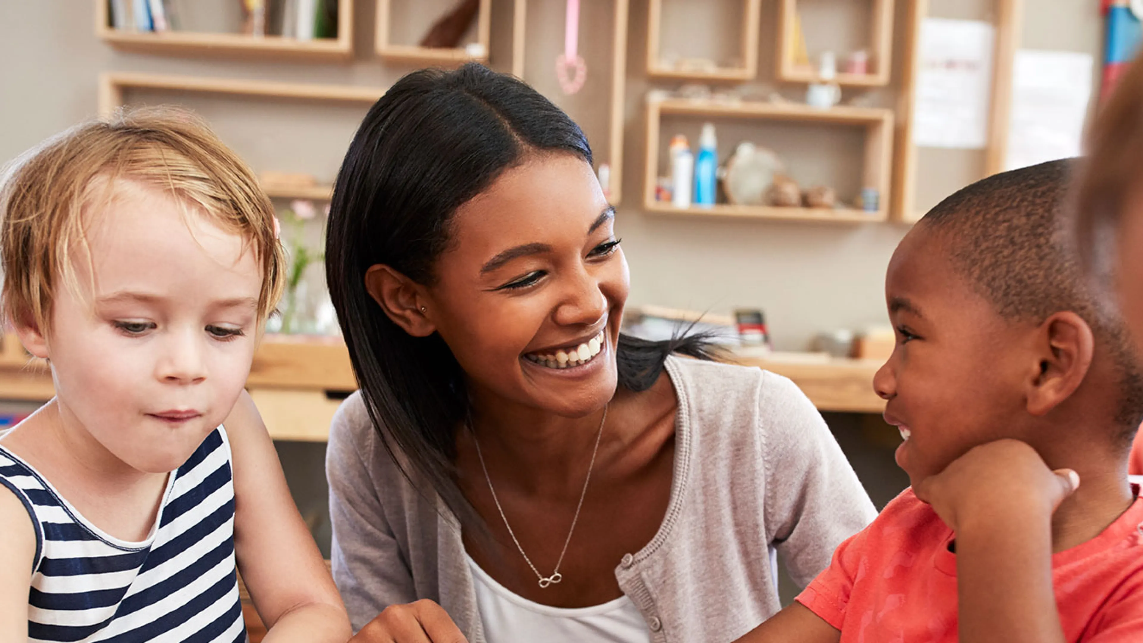 child care worker helping children with shape puzzle