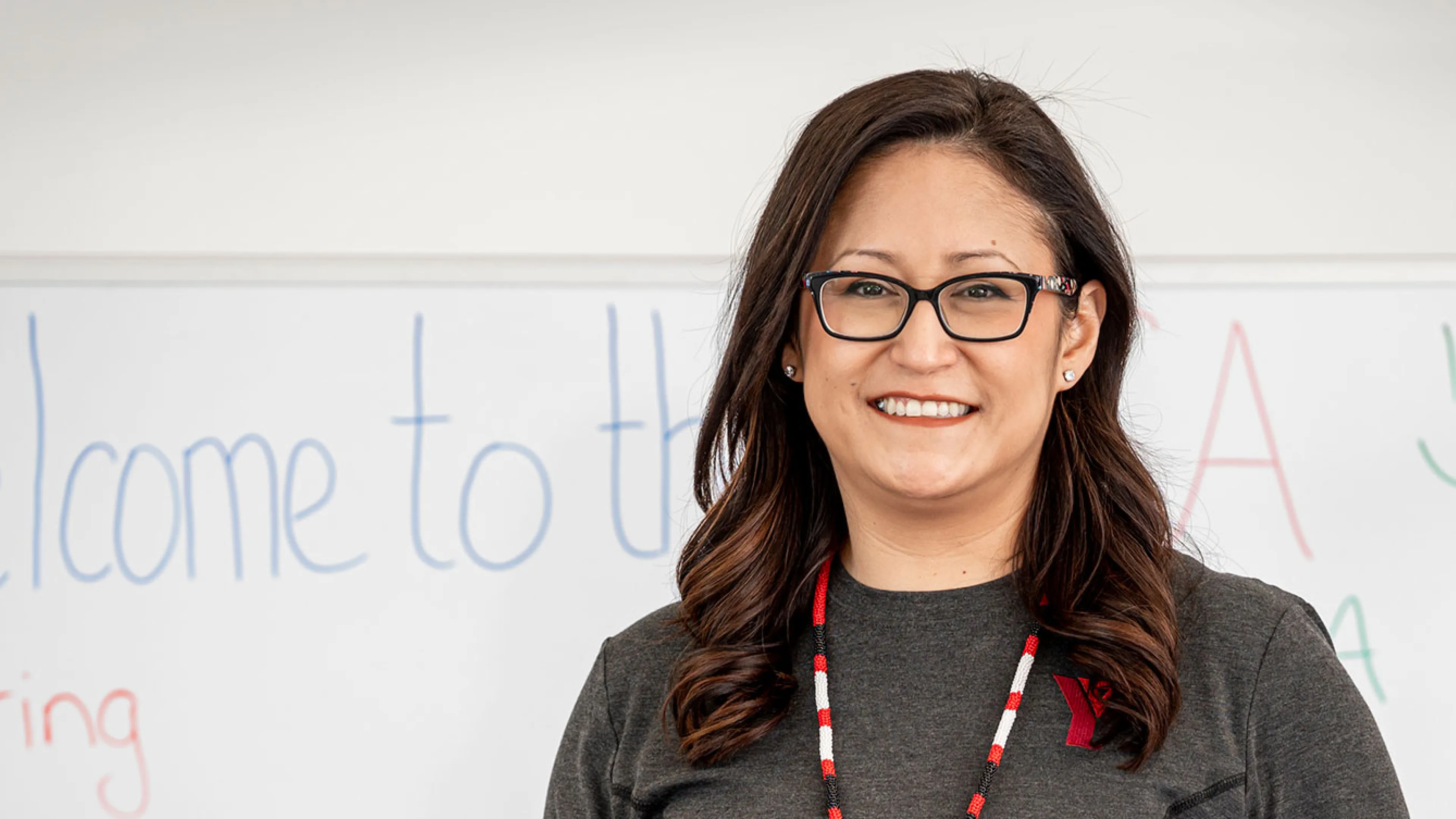 Smiling employee in front of whiteboard that says Welcome to the YMCA
