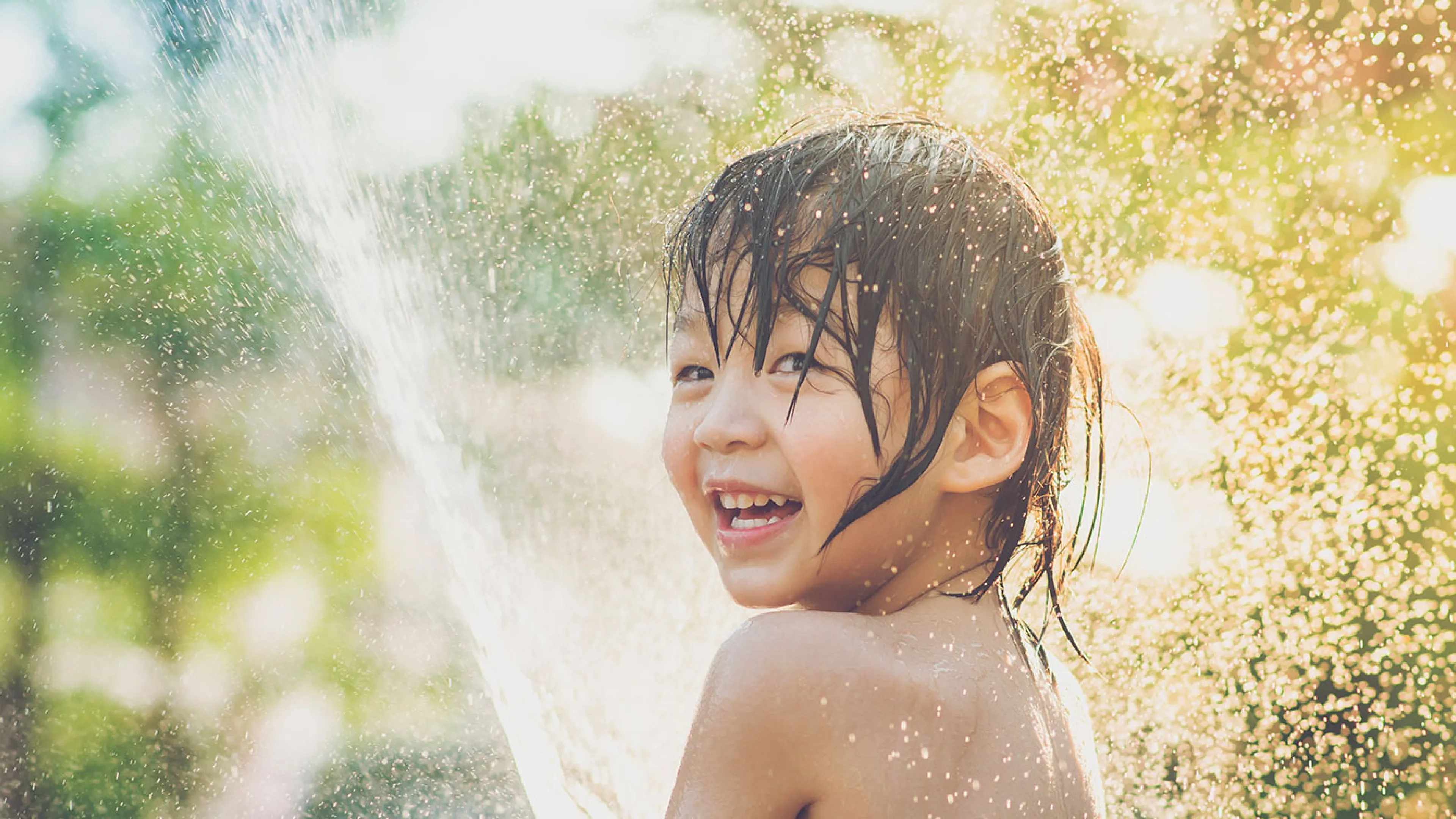 happy child playing with water in sunshine