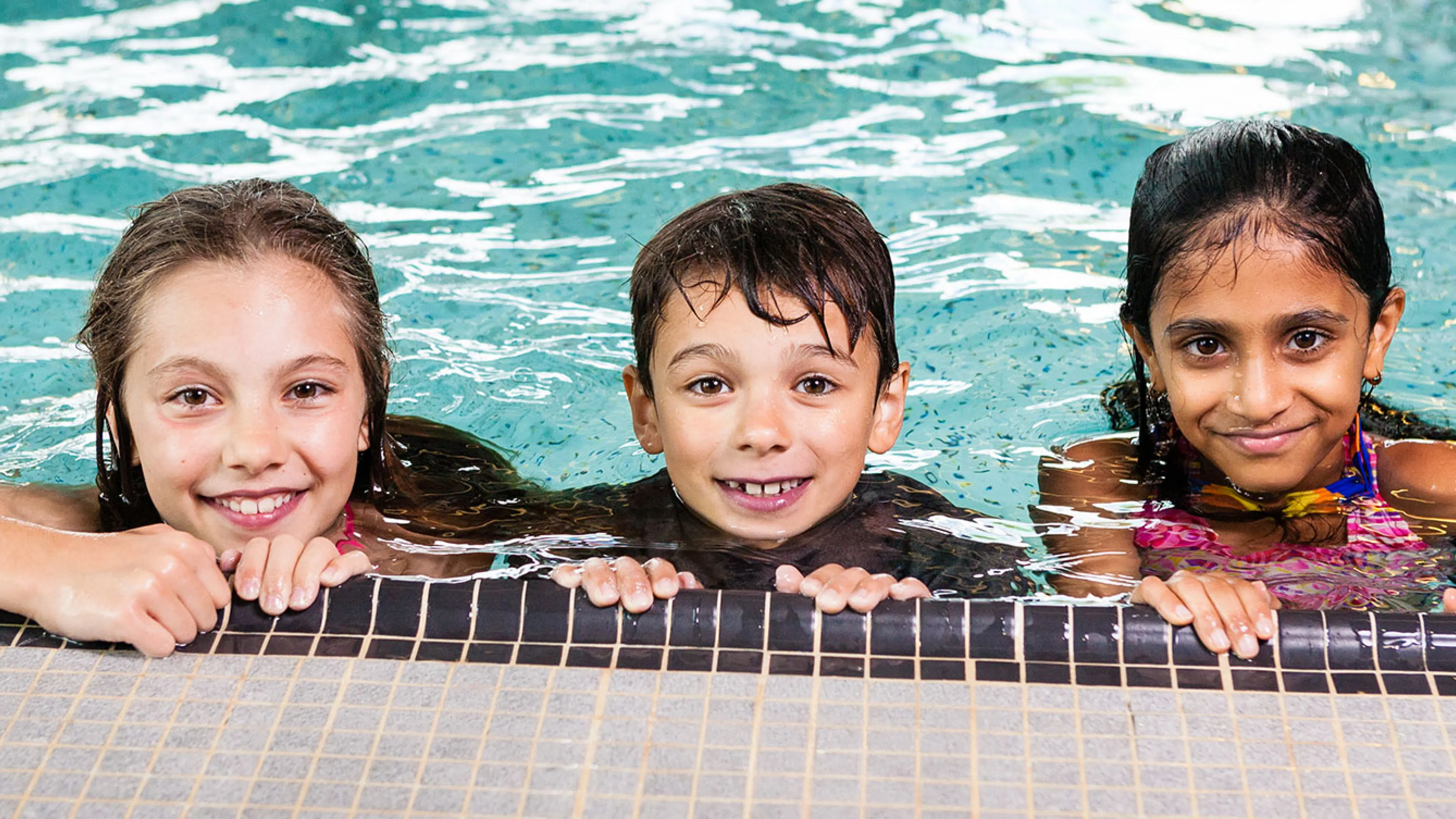 three happy children in a pool