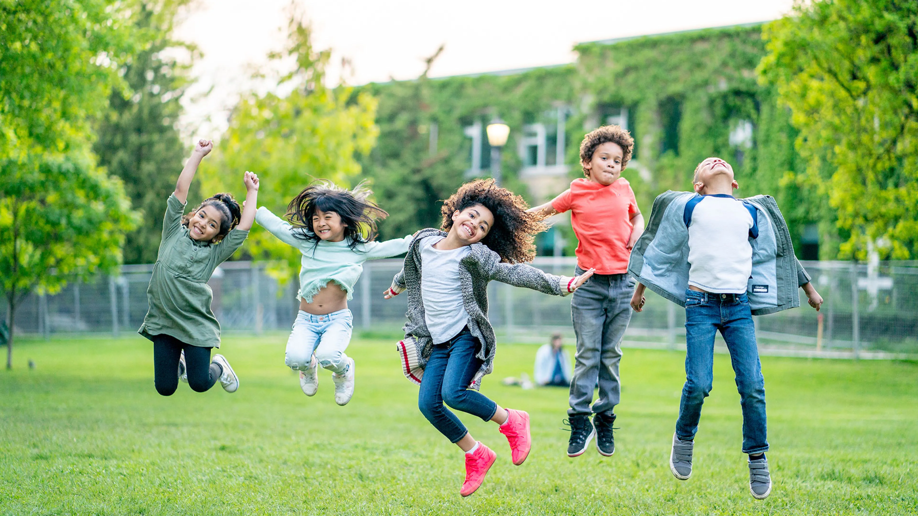 group of children jumping in a grassy field