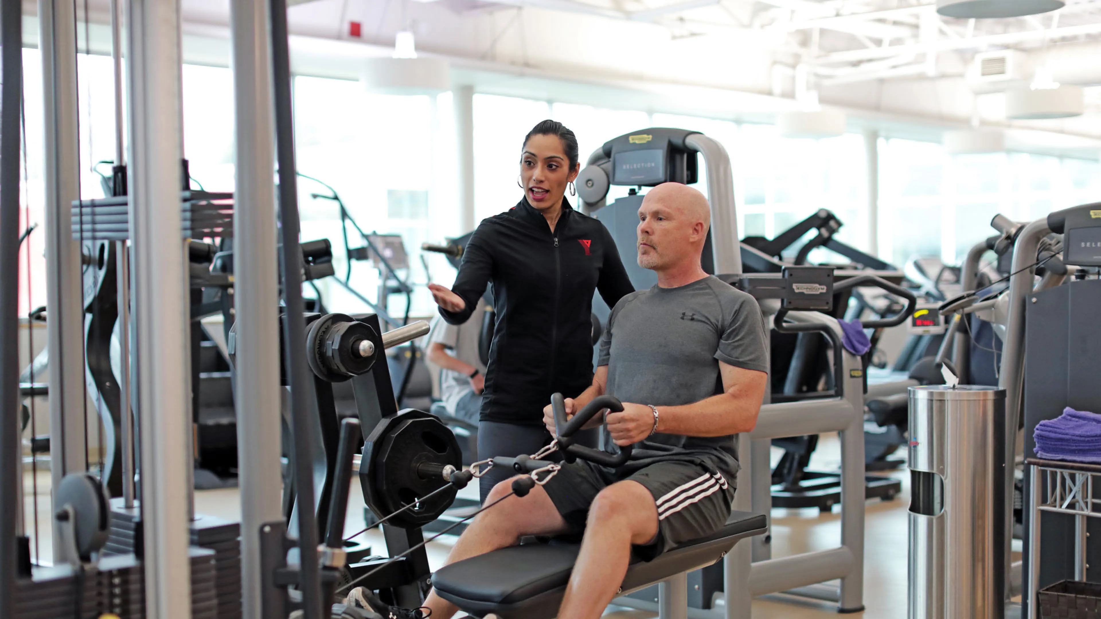 YMCA staff showing a member how to use a fitness machine