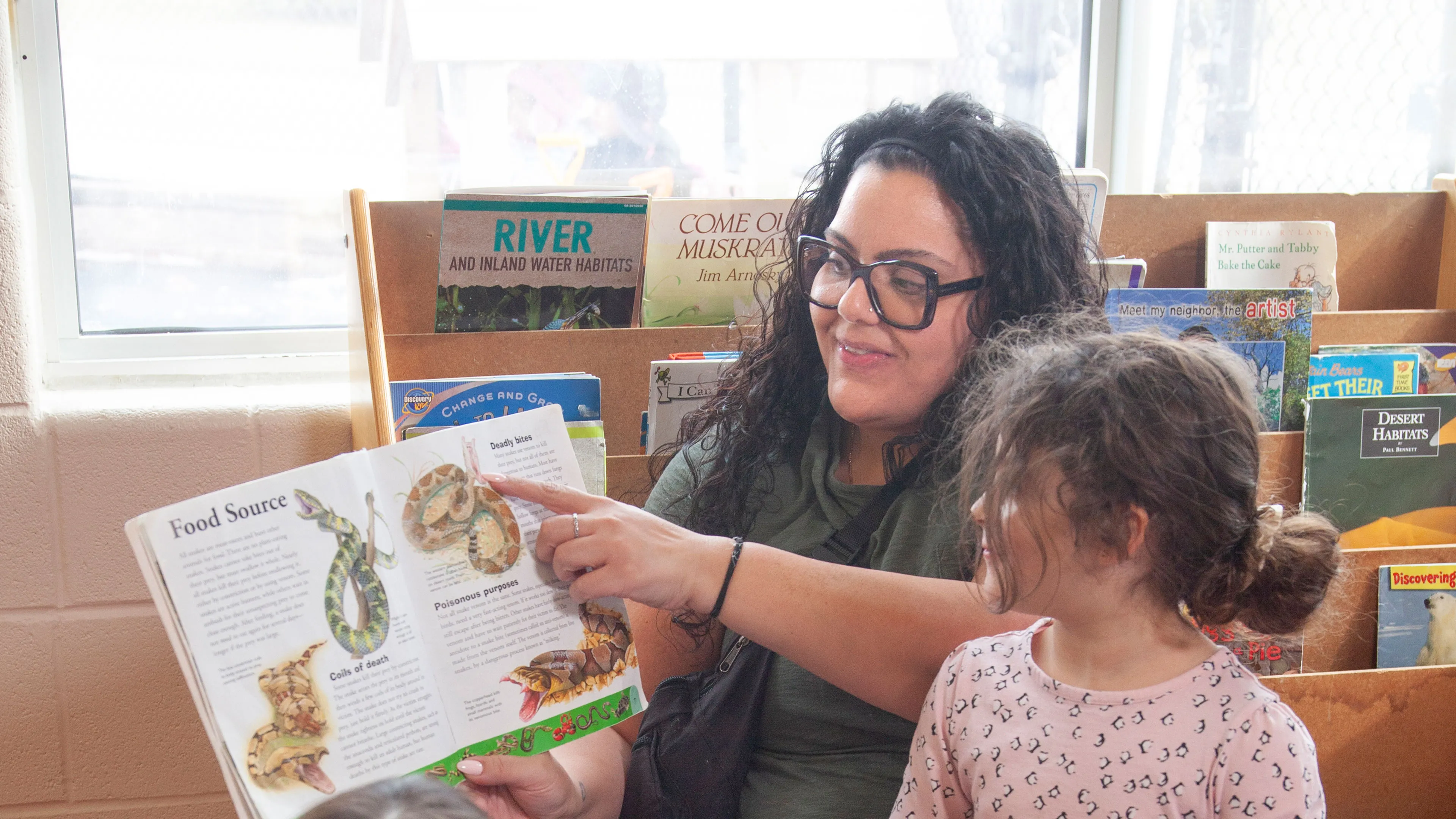 child care worker reading a book about snakes to children