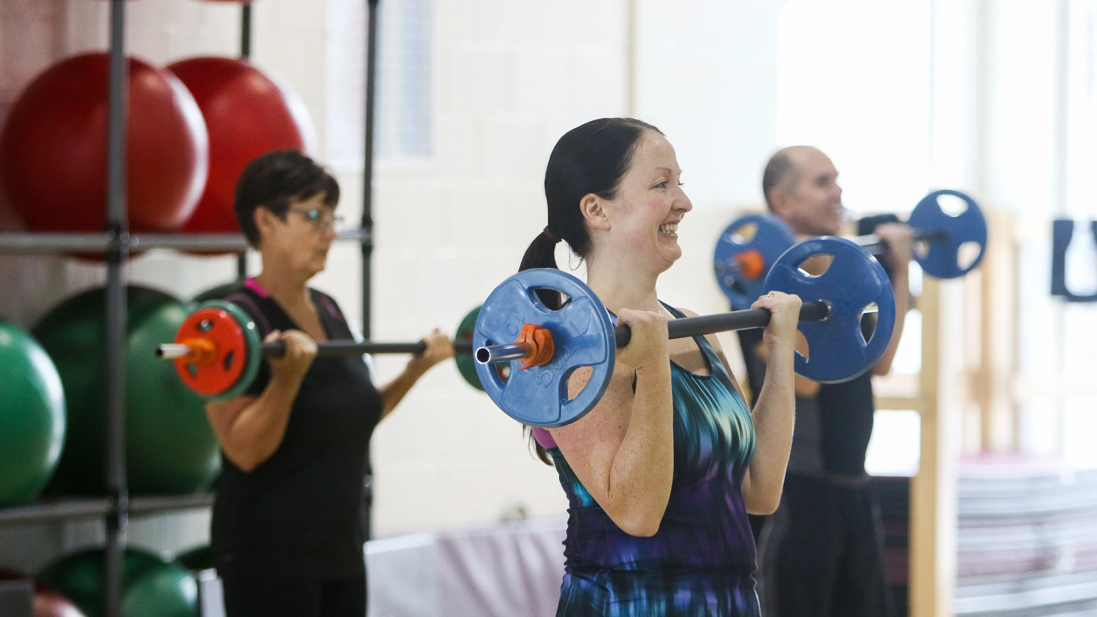 group fitness class participants doing barbell bicep curls