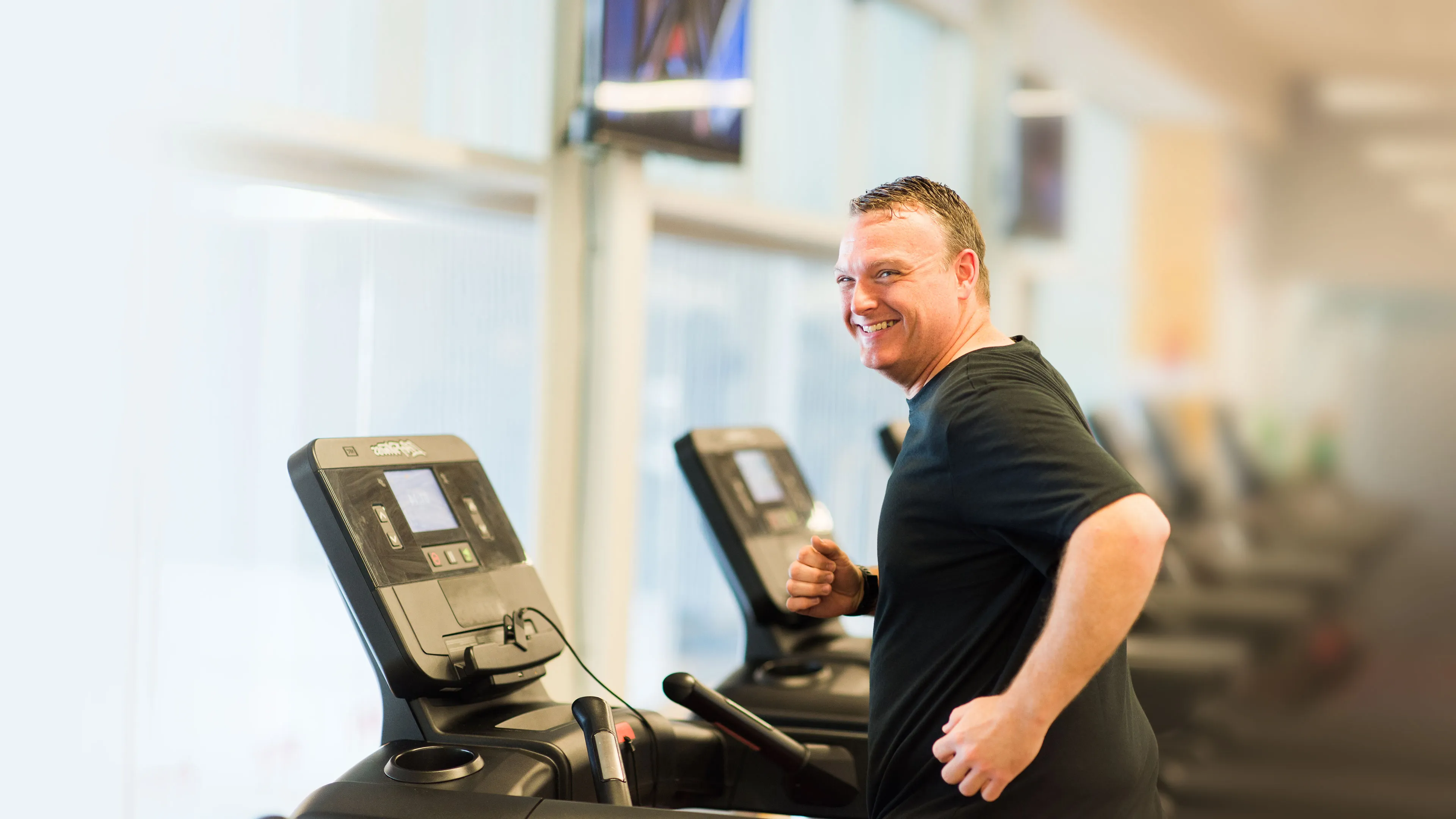 happy middle-aged man jogging on treadmill