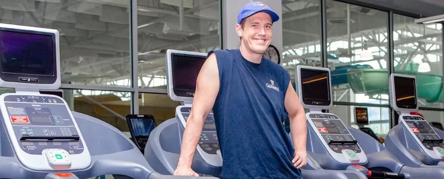 Austin smiling in front of the elliptical machines 