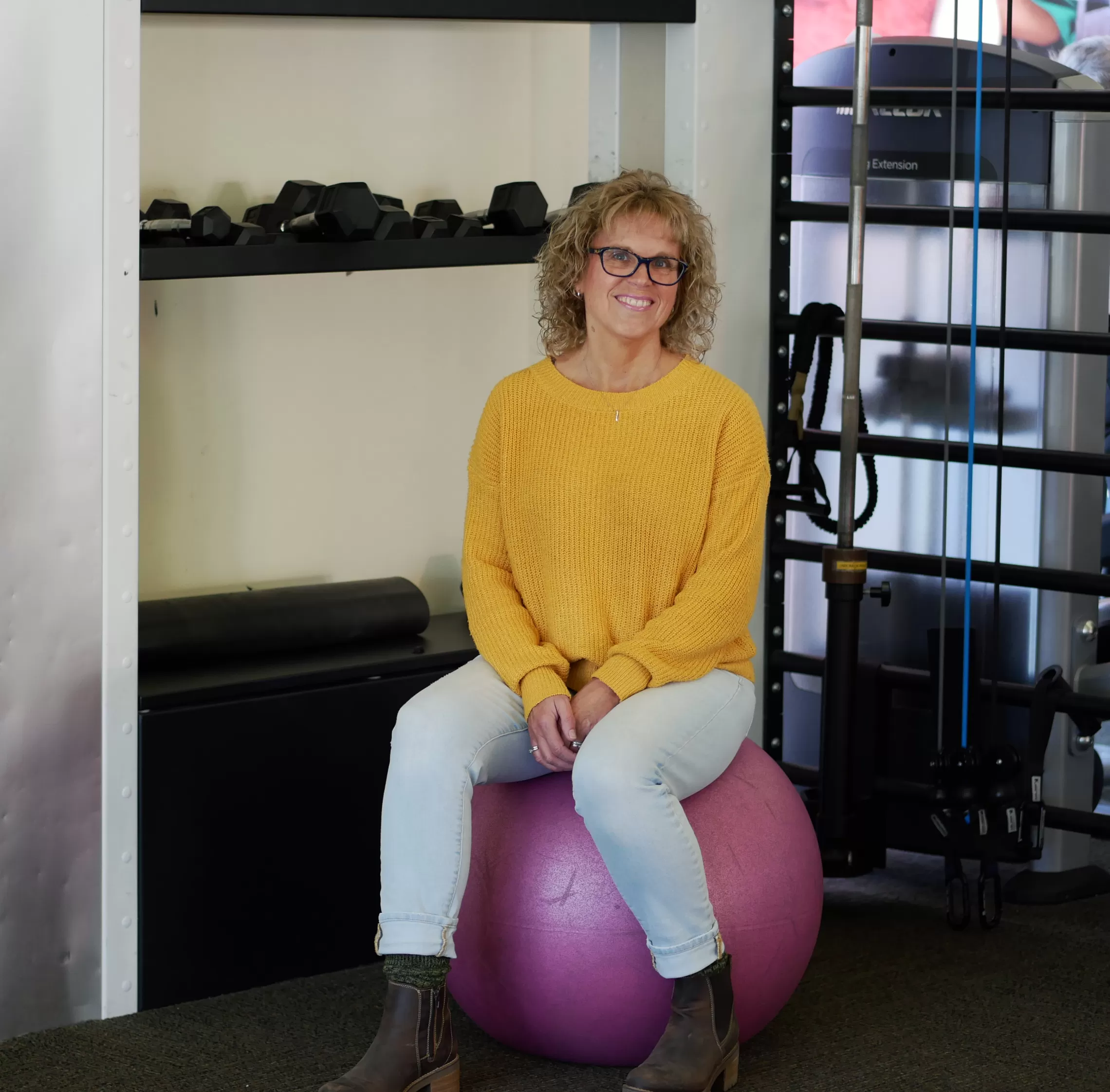 woman in yellow sweater sitting on a yoga ball