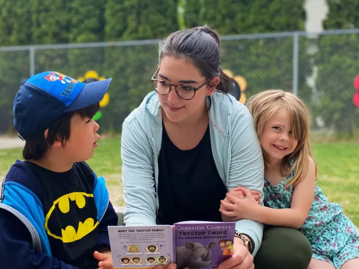 2 children and a woman reading a book