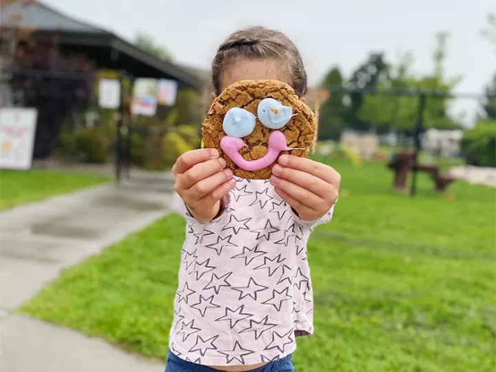 Kid holding up cookie on face
