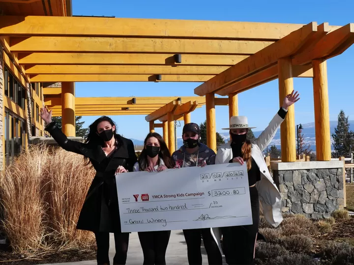 4 women outside holding a big cheque