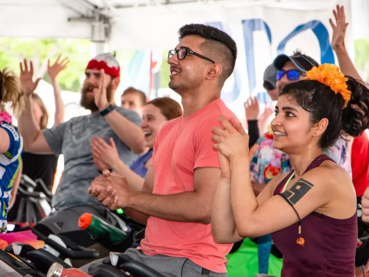 people raising their hands on bikes