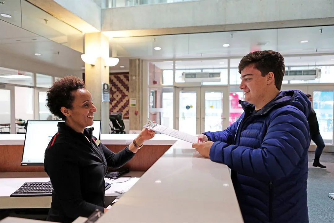 YMCA staff handing form to young adult